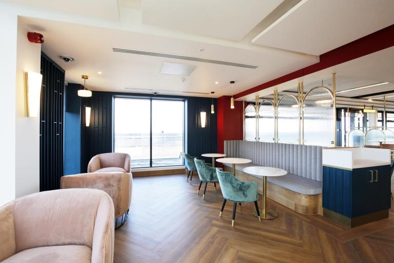 Interior of a lounge bar inside the Regent with large windows towards the sea, and modern furniture