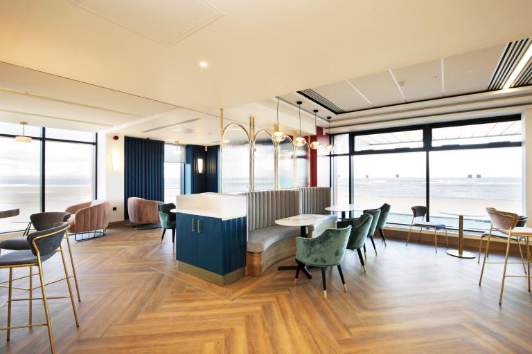 Interior of a lounge bar inside the Regent with large windows towards the sea, and modern furniture