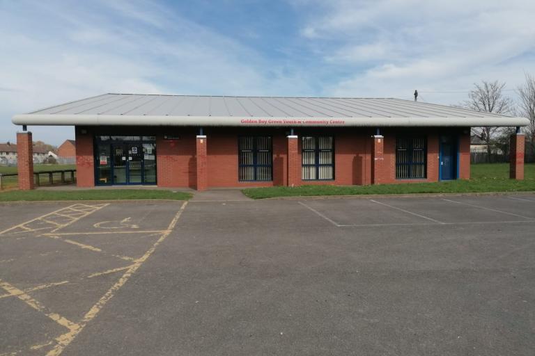 Image of the Golden Boy Green Youth and Community Centre from the front entrance with the car park