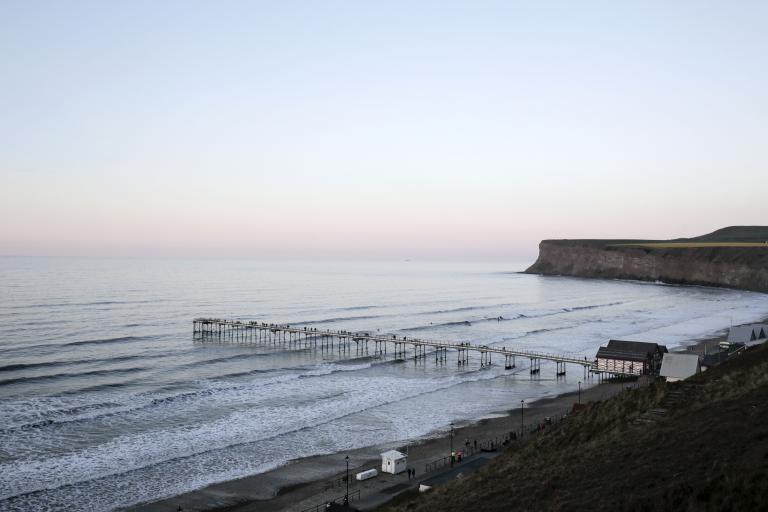 Image of Stalburn beach and pier from the top of the hills with the cliffs in the background.