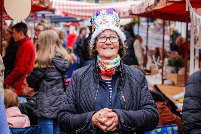 Woman wearing a festive crown at the Chaloner Street Market with crowds and stalls in the background.