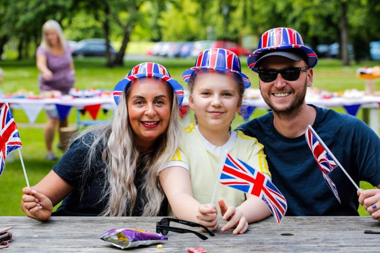 Mother, father and son holding the UK flags and wearing themed hats at the Tea Party at Kirkleatham Museum.