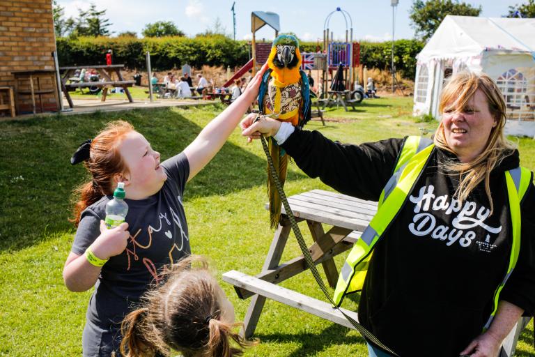 Image of a young girl petting a parrot held by it's trainer at the Jubilee Fete.