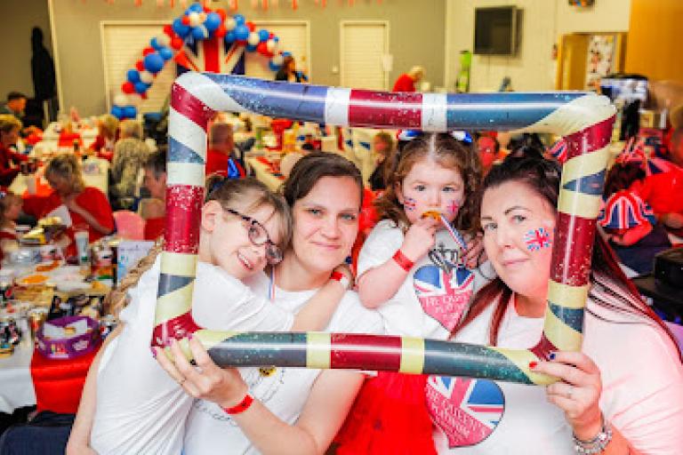 Image showing a happy family, a woman with her three daughters, taking a Jubilee themed picture at the Whale Hill party.