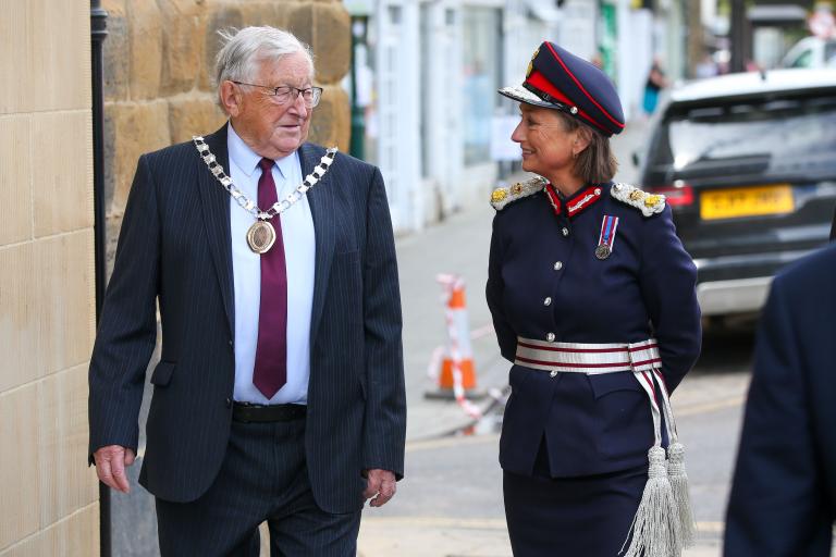 Image of Councillor Malcolm and Lord Lieutenant, Mrs Johanna Ropner, walking down Westgate in Guisoborugh. A black vehicle is visible in the background.