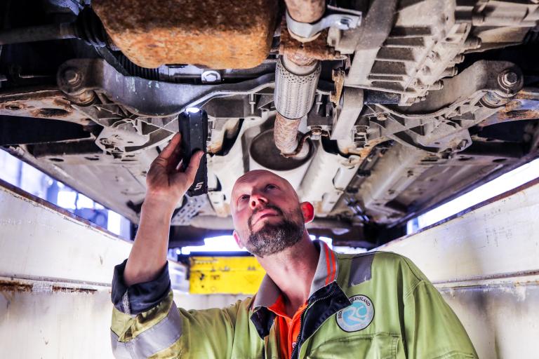 Image of a MOT tester and fitter hard at work fixing a car at the depot.