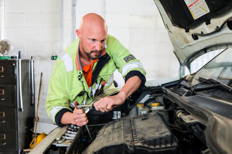Image of a MOT tester and fitter hard at work fixing a car engine