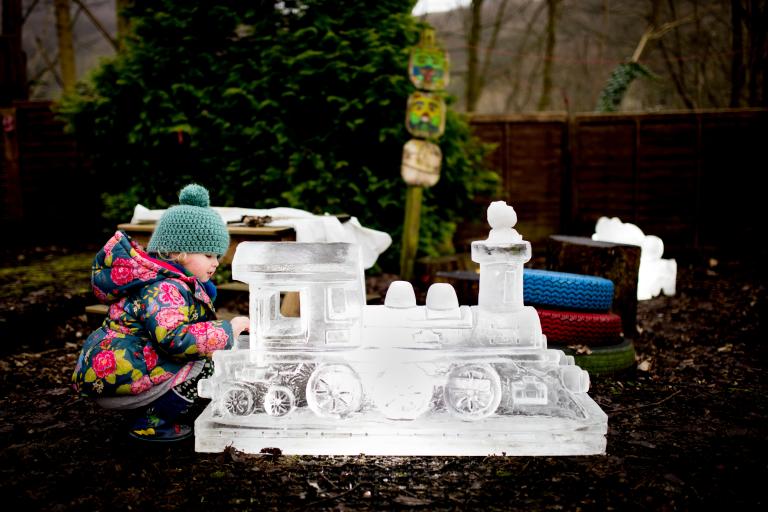 A young girl admiring the Hebden Bridge Ice Sculptures of a train.