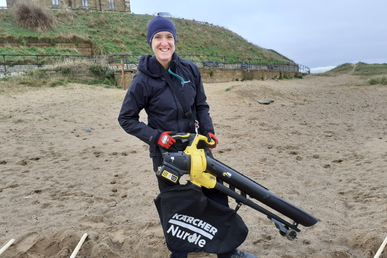 Image of one of the Marske Litter Action volunteers on the Marske beach using a vaccum to remove microplastics from sand.