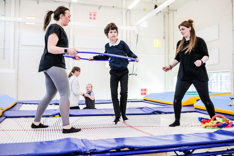 Image of two female teachers and a young boy having fun on a trampoline. 