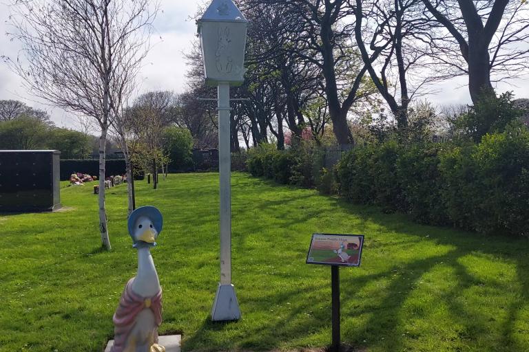Image of the Peter Rabbit Garden in the Redcar Cemetery, figure of Jemina the Duck next to an engraved lamp