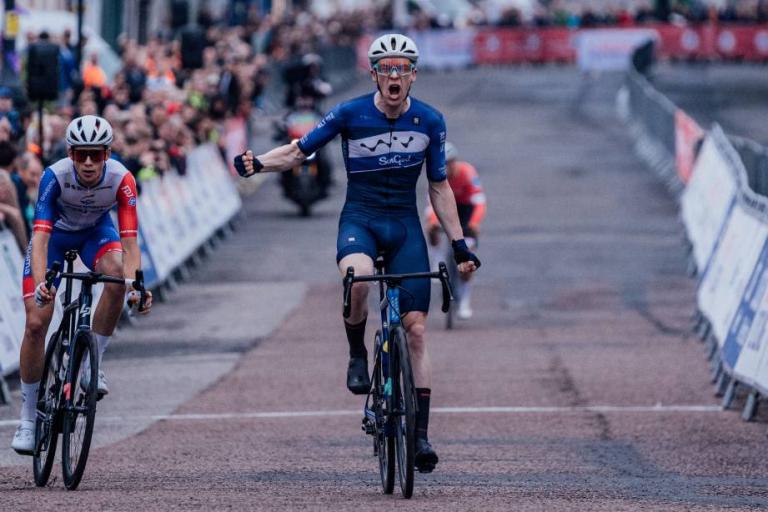 Image of a cyclist wearing a blue jersey celebrating winning a race.
