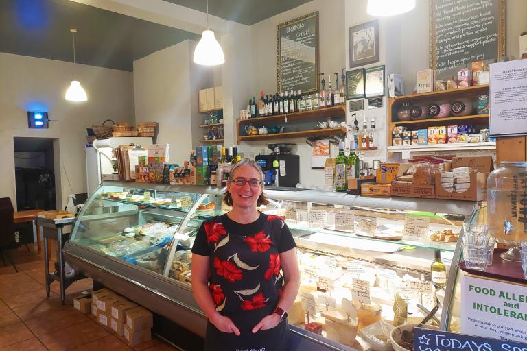 Image of a lady dressed in a red an black shirt standing in a café