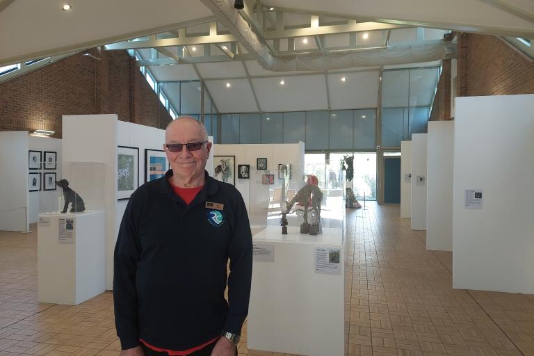 A man standing in the middle of an art exhibition depicting dogs