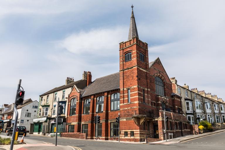 picture of a red bricked church located at a junction 