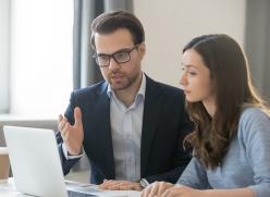 Image of a man and woman having a conversation whilst looking at a laptop screen