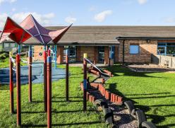 Image of the Grangetown Family Hub with the building in the background and a playground in the front.