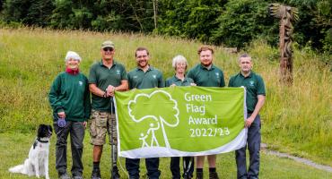 Image of park rangers wearing green shirts holding a sign that reads green flag award 2022/23