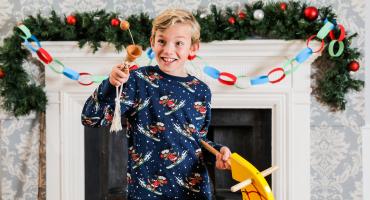 Image a child wearing a christmas jumper playing with a yellow horse toy