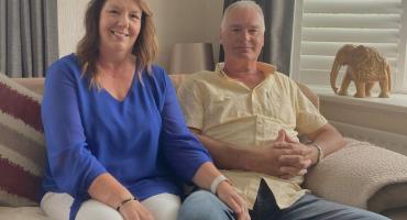 Image of a man and women sitting on a cream sofa. 