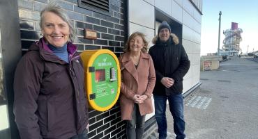 (from left t right) Cllr Ursula Earl, Karen Davies, Cllr Carl Quartermain standing next to the defibrillator installed outside the Regent