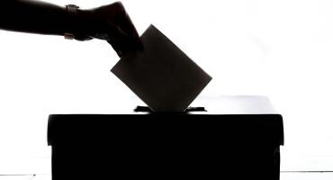 Image of a hand putting a ballot in a black box