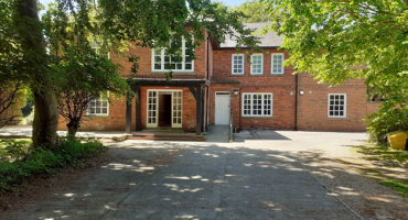a driveway framed by trees leading to a re-bricked building