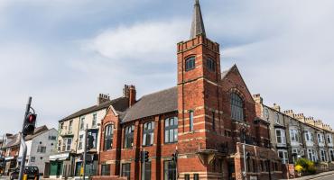 picture of a red bricked church located at a junction 