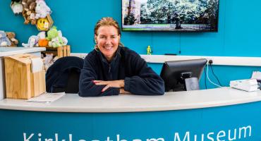 A woman sitting behind a reception desk to Kirkleatham Museum