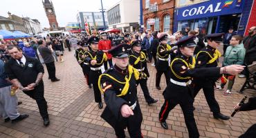 Image shows armed forces cadets wearing their uniforms marching down a street.