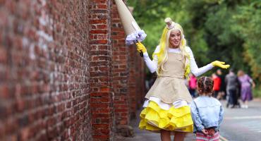 Image shows a lady dressed in yellow talking to a child.
