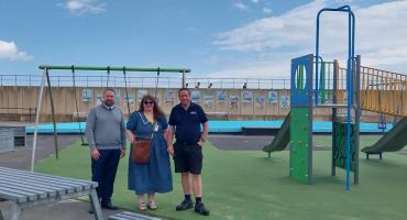 Two man and a woman standing in the middle of a play area on a sunny day