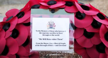 The picture depicts a  wreath made out of artificial poppy flowers
