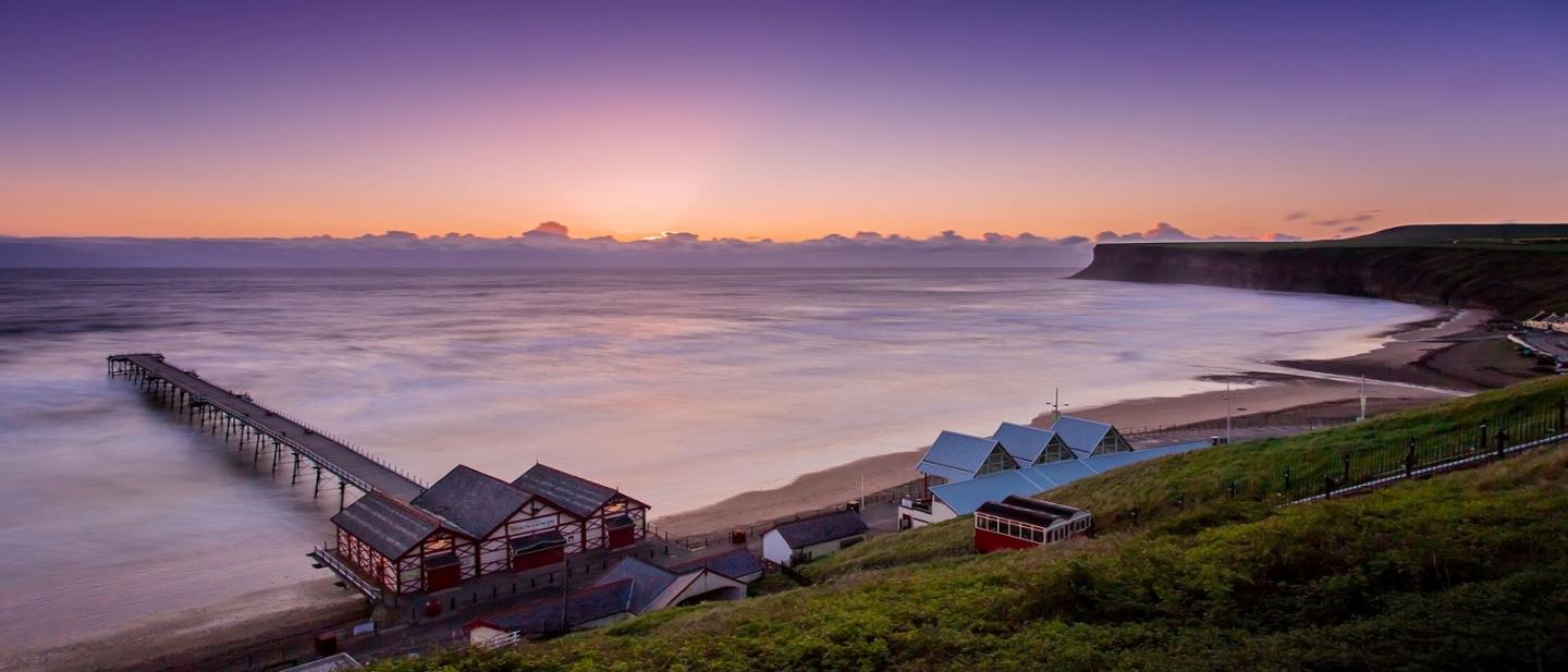 Saltburn pier at dawn with warm red skies 