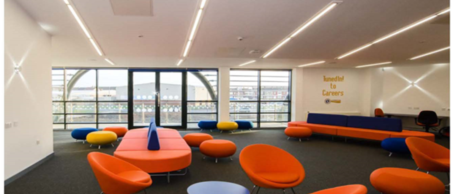 Image of the chill out area in the centre with two long circular couches, modern chairs and neon lights on the ceiling.