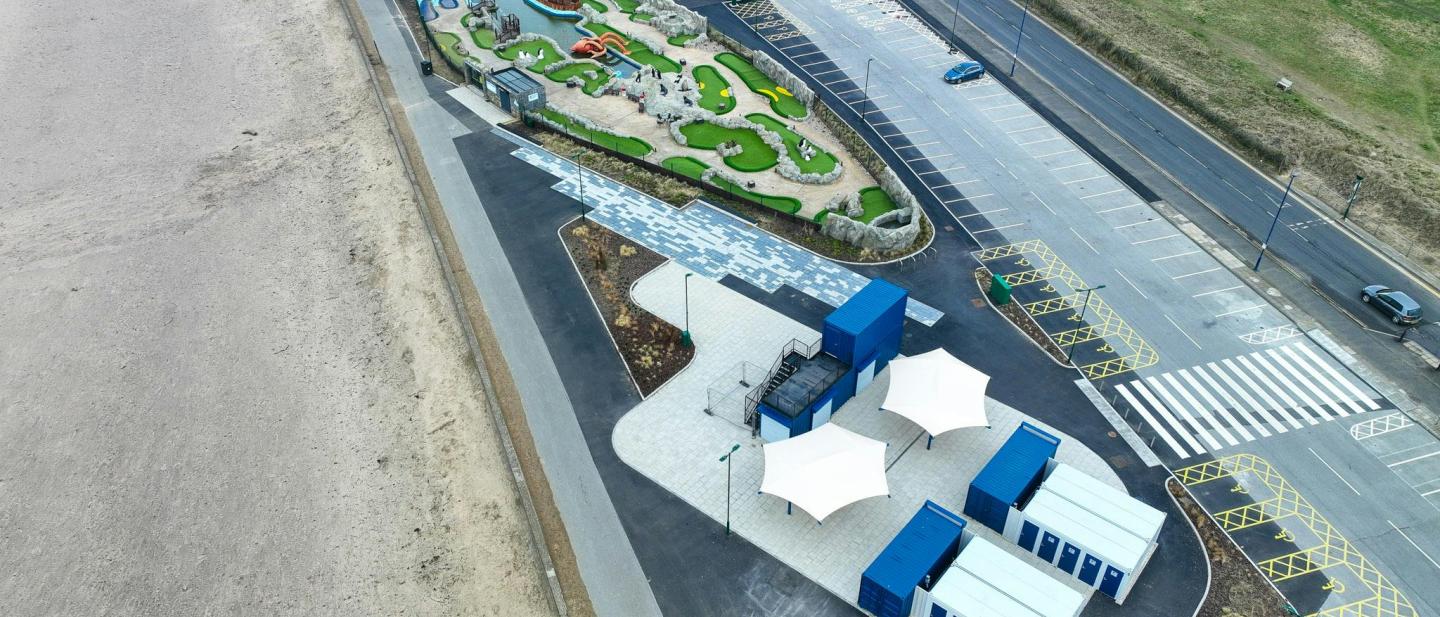 Image of Redcar Beach Base. The image shows the blue containers that make up the location with the adventure mini golf course in the background.
