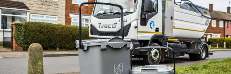 Image shows a food waste collection vehicle in the background with the food waste caddy and container in the foreground.