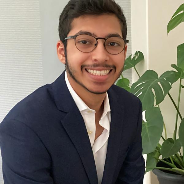 Image of a young man dressed in a suit and smiling at the camera.